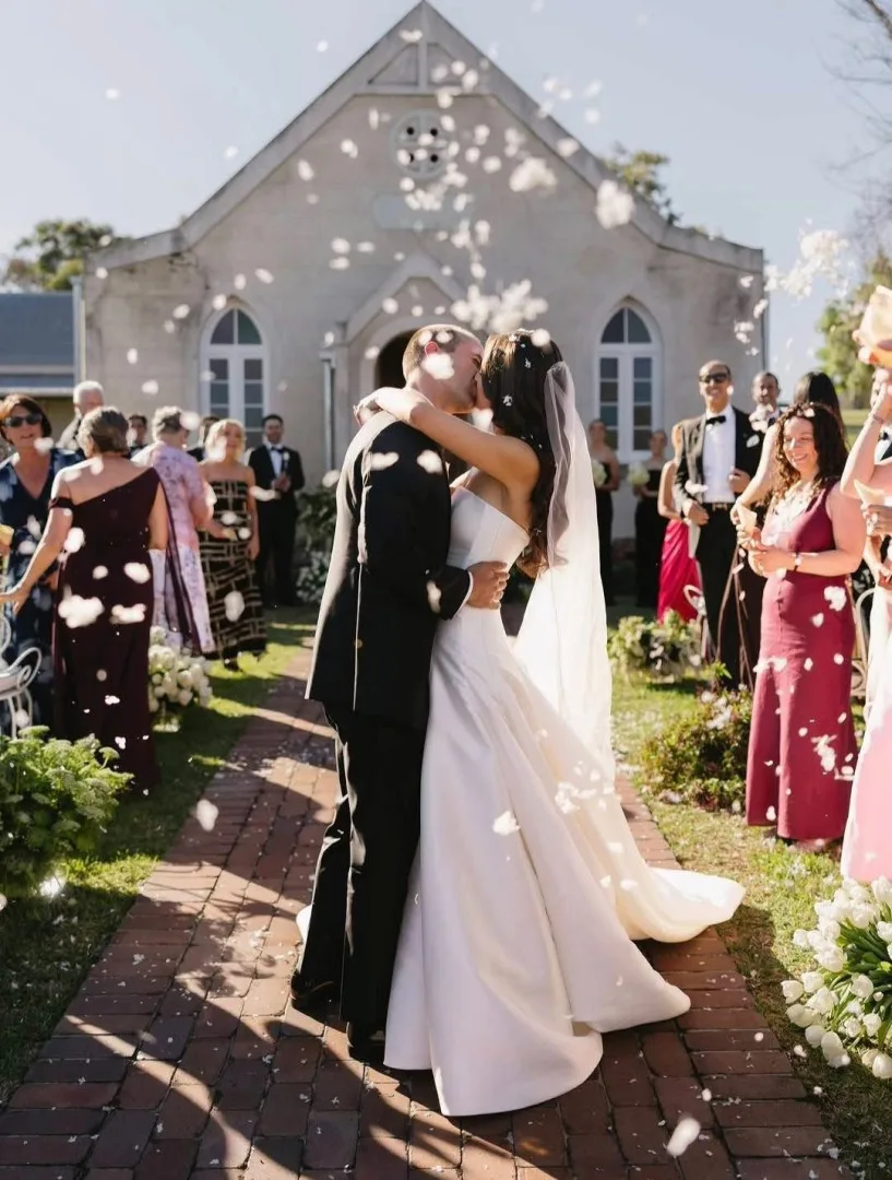 Bride and groom under falling confetti, with bridal hair by Runway Tamworth