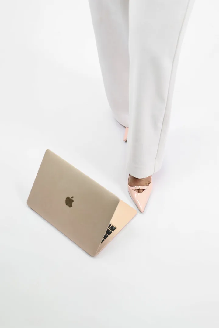 Pink heels beside a gold laptop, ready to contact Runway hair and beauty salon in Tamworth